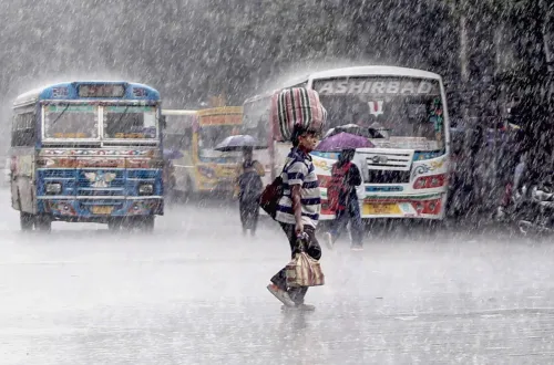 कोलकाता में बारिश के बीच सड़क पर राहगीर