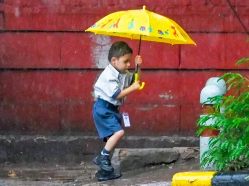 स्कूली बच्चा छाते के साथ भारी बारिश में नई दिल्ली की सड़क पर