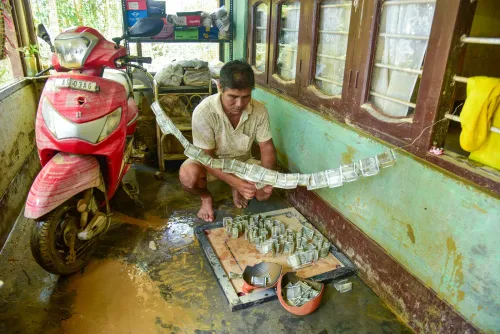 जोरहाट: बाढ़ में डूबे घर में गीले नोट सुखाता ग्रामीण